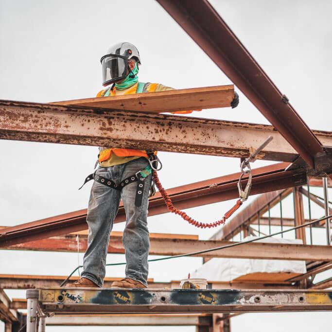 Construction worker standing on scaffolding high up on a job site.